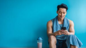 フィットネスアプリで管理しながらプロテインを飲む男性